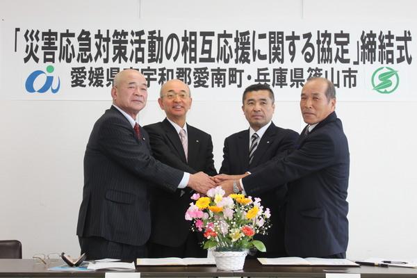 災害応急対策活動の相互応援に関する協定締結式にて、市長と、男性3名が手を重ねている写真